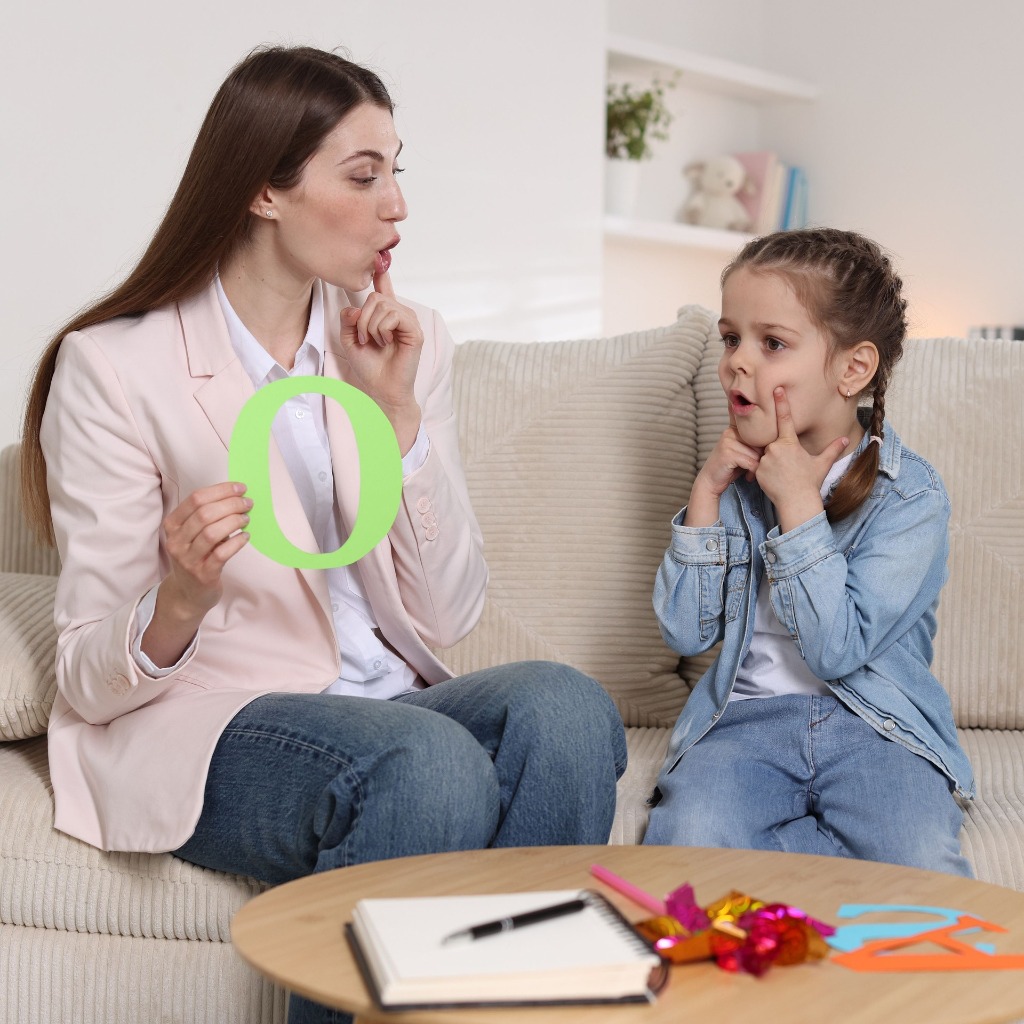 Speech therapist teaching letter sounds to a child in a calm clinical setting